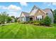 Inviting home featuring a manicured lawn, a mix of stone and siding, and mature landscaping at 10903 Skymont Dr, Huntersville, NC 28078