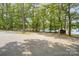 Expansive gravel area by the lake, shaded by mature trees, perfect for parking and recreational activities at 1102 Lake Montonia Rd, Kings Mountain, NC 28086