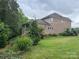Manicured backyard with lush lawn, mature trees, and brick facade at 1124 Greenbridge Dr, Matthews, NC 28105