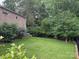 Large backyard featuring well-maintained lawn, mature trees, and a brick house on the left side at 1124 Greenbridge Dr, Matthews, NC 28105