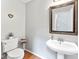 Charming powder room with pedestal sink, framed mirror, and hardwood floors at 116 Oak Creek Dr, Charlotte, NC 28270