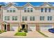 Exterior view of townhomes showcases a blend of brick and siding, complemented by attached garages and landscaping at 117 Langhorne Dr, Mount Holly, NC 28120
