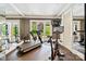 Well-lit exercise room with treadmill, bike, mirrored walls, and access to outdoor patio at 11710 Ney Manor Way, Charlotte, NC 28277