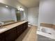 Bathroom featuring double vanity, large mirror, soaking tub, and separate toilet area, exuding comfort at 129 Steinbeck Way, Mooresville, NC 28117