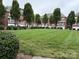 View of lush green community lawn with mature trees and townhomes at 129 Steinbeck Way, Mooresville, NC 28117