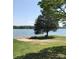 Stunning lake view with a sandy beach, picnic table, and shady tree perfect for relaxing by the water at 134 Crystal Cir, Mooresville, NC 28117