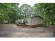 Exterior view of a charming single-level home with a gravel driveway and surrounded by tall, mature trees at 1789 Paris Dr, Conover, NC 28613