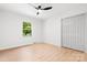 This empty bedroom features a ceiling fan, light wood floors, white walls, a window, and a white closet door at 201 Forest Rd, Taylorsville, NC 28681