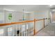 Hallway with wood banister overlooking living room with fireplace and large windows, creating an open and airy feel at 201 Limerick Dr, Matthews, NC 28104