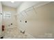 Laundry room with tile floor, window, utility connections, and wire rack shelving for ample storage at 201 Limerick Dr, Matthews, NC 28104