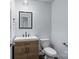 Powder room with wood grain vanity, white sink, black faucet, black framed mirror, and white toilet at 2021 Tarzi Ln, Charlotte, NC 28215