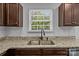 Kitchen featuring dark cabinets, granite countertops, stainless steel sink, and a view of greenery outside at 2021 Tarzi Ln, Charlotte, NC 28215