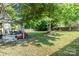 Large backyard with patio featuring dining and seating areas, mature trees, and lush lawn at 2206 Waters Trail Dr, Charlotte, NC 28216