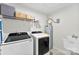 Efficient laundry room featuring modern washer and dryer, shelf for storage, and utility sink at 2217 Goldwood Dr, Charlotte, NC 28215