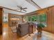 Cozy living room with wood paneled walls, large windows, ceiling fan, and hardwood flooring at 3225 Mill Pond Rd, Charlotte, NC 28226