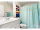 Well-lit bathroom with a white vanity, colorful art, and charming sailboat-themed shower curtain at 424 River Park Rd, Belmont, NC 28012