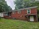 The rear of the brick home with multiple windows, a covered porch and outdoor entry at 4520 Bradbury Dr, Charlotte, NC 28209