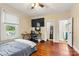 This bedroom has hardwood floors, a large window, a tv, and an ensuite bathroom with a glass door shower at 454 N Eastway Dr, Troutman, NC 28166