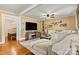 Comfortable living room featuring a plush sofa, large TV, hardwood floors, and decorative ladder shelving at 454 N Eastway Dr, Troutman, NC 28166