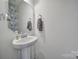 Elegant half bathroom featuring a pedestal sink, stylish mirror, and decorative wallpaper accent at 5125 Thomasville Dr, Belmont, NC 28012