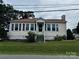 Exterior view of charming home featuring neutral siding, dark shutters, covered front porch, and green lawn at 522 W Congress St, Lincolnton, NC 28092