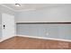 Empty room with gray walls, white door, and wood floors at 7101 Agnew Dr, Charlotte, NC 28273