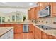 Bright kitchen featuring granite countertops, wooden cabinets, stainless steel appliances, and hardwood floors at 7480 Katelyn Ct, Harrisburg, NC 28075