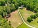 Aerial view of a sprawling property with a long driveway, fenced pastures, and a home surrounded by trees at 7712 Old Waxhaw Monroe Rd, Waxhaw, NC 28173