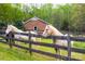 Tranquil scene of horses grazing in a green pasture, enclosed by a rustic wooden fence with building in the background at 7712 Old Waxhaw Monroe Rd, Waxhaw, NC 28173