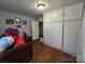 A blue toned bedroom with a ceiling light, hardwood floors, and white storage cabinets at 804 Dennis St, Troy, NC 27371