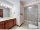 A well lit bathroom featuring wood cabinets, linoleum floors, and a shower at 965 Hunting Ave, Lincolnton, NC 28092