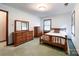 A well lit bedroom with matching dressers, a wood framed bed, and neutral walls and carpeting at 965 Hunting Ave, Lincolnton, NC 28092