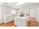 White kitchen featuring a functional island, stainless steel appliances, and ample cabinet space with beautiful hardwood floors at 114 Sardis Plantation Dr, Matthews, NC 28105