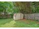 Backyard view featuring a storage shed with double doors, fenced yard, and green grass at 114 Sardis Plantation Dr, Matthews, NC 28105