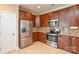 Stylish kitchen featuring stainless steel appliances, tile floors, granite counters, and brown cabinets at 11607 Meetinghouse Dr, Cornelius, NC 28031