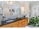 Bathroom with double sinks, wood cabinets, large mirror, black granite counters, and black and white mosaic tile floor at 141 Eastover Se Dr, Concord, NC 28025