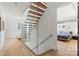 Modern staircase with glass railing and wood treads, leading to a bedroom with blue bedding, creating an open and airy feel at 1620 S Tryon St, Charlotte, NC 28203