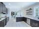 Bright, open kitchen with black cabinetry, quartz countertops, and a view into the adjacent dining and living areas at 2000 Plainfield Dr, Bessemer City, NC 28016