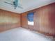 Modest bedroom with wood-paneled walls, ceiling fan, and carpeted floors offers cozy potential at 201 Robinson Rd, Gastonia, NC 28056