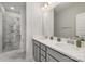 Bathroom featuring double sinks, gray cabinetry, and a walk-in shower at 235 S Bruns Ave, Charlotte, NC 28208
