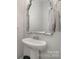 Pedestal sink with a decorative mirror and a chrome faucet in the powder room at 235 S Bruns Ave, Charlotte, NC 28208