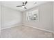 Minimalist bedroom with plush carpet, ceiling fan, and a window offering neighborhood views at 2760 Berkhamstead Cir, Concord, NC 28027