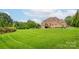 Sprawling backyard featuring lush green grass and a brick home with a deck at 3009 Ocaso Ct, Matthews, NC 28104