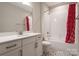 Bathroom with a white vanity, white countertop, brushed nickel fixtures, and a tub with a red patterned shower curtain at 3009 Ocaso Ct, Matthews, NC 28104