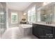 Spa-like bathroom with a soaking tub, elegant vanities, marble accents, and lots of natural light at 3009 Ocaso Ct, Matthews, NC 28104