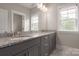 Bathroom featuring double sinks, gray cabinets, granite countertops and a large mirror with modern lighting fixture at 3009 Ocaso Ct, Matthews, NC 28104