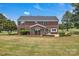 Landscaped backyard features a brick home, a stone patio, and mature trees at 3068 River Rd, Shelby, NC 28152