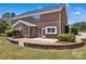 Backyard featuring a brick home exterior with a stone patio and lush landscaping at 3068 River Rd, Shelby, NC 28152