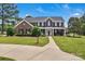 Stunning brick home with a lush green lawn, mature trees, and a welcoming walkway leading to the covered front porch at 3068 River Rd, Shelby, NC 28152