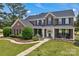 Charming two-story brick home featuring a manicured lawn, lush landscaping, and inviting front porch with rocking chairs at 3068 River Rd, Shelby, NC 28152
